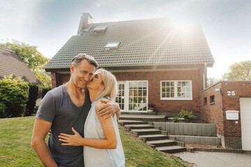 Portrait of smiling mature couple embracing in garden of their home