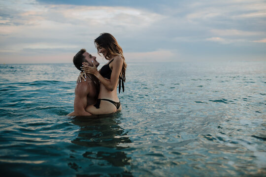 Young couple doing romance in water at beach during sunset