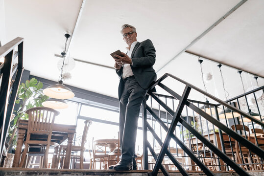Senior businessmans standing at railing, using digital tablet