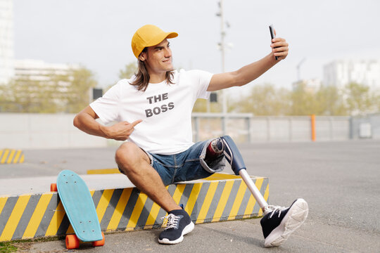 Smiling disabled man taking selfie while sitting on road in city