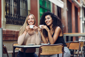 Two happy friends drinking coffee in sidewalk cafe