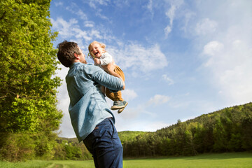 Father holding happy baby in the nature