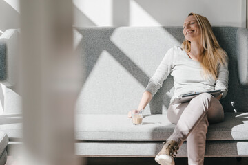 Smiling woman relaxing on couch with laptop