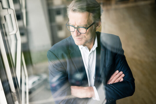 Serious mature businessman looking out of window