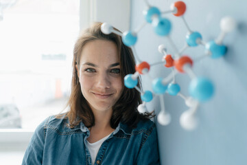 Female scientist studying molecule model, looking for solutions