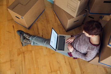 Woman using laptop with rising line graph on the screen in a new home