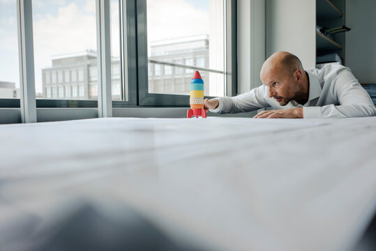 Businessman playing with toy rocket in office