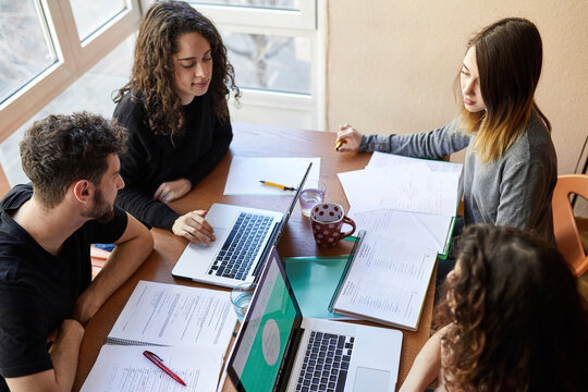 Four students at desk working and learning together
