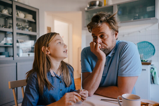 Daughter talking to father in kitchen at home