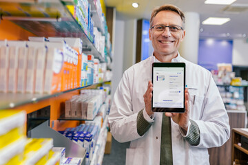 Portrait of smiling pharmacist in pharmacy holding tablet with digital order