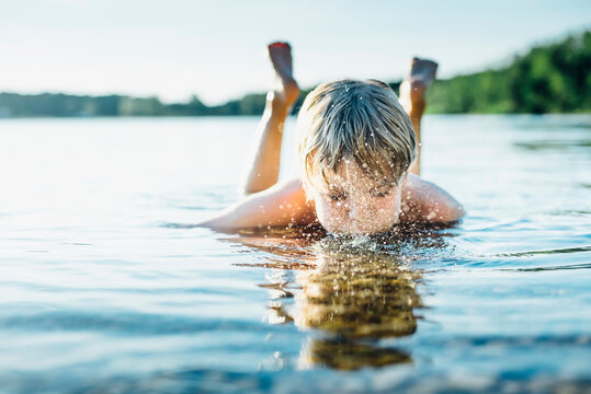 Boy in a lake blowing into water