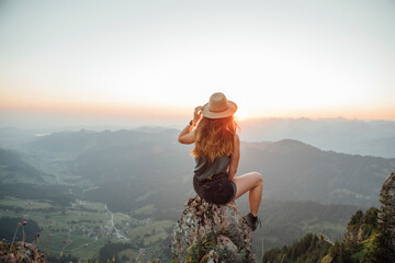 Switzerland, Grosser Mythen, young woman on a hiking trip sitting on a rock at sunrise