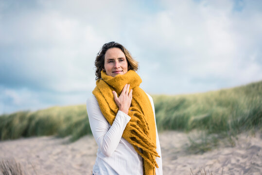 Mature woman relaxing in the dunes, enjoying the wind - Powered by Adobe