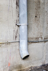 Vertical drain pipe on dirty concrete wall.