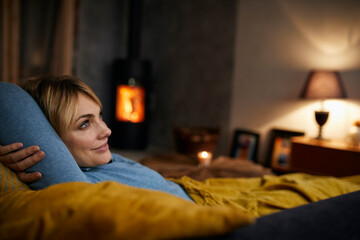 Smiling woman relaxing on couch at home in the evening