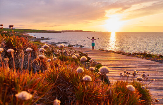 Italy, Sardinia, Lu Litarroni, senior woman on wooden boardwalk at sunset