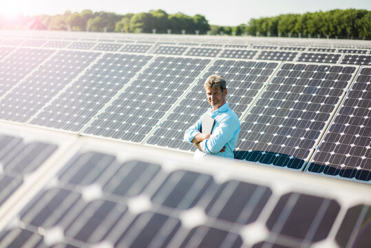 Mature man with laptop standing in solar plant