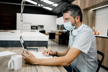 Businessman wearing protective mask while using laptop at desk in office during COVID-19 pandemic