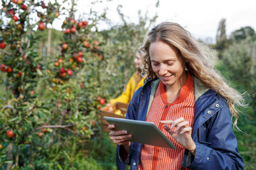 Smiling woman using tablet in apple orchard