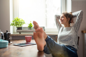 Woman sitting at table in kitchen relaxing