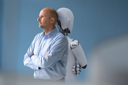 Businessman standing back to back with robot