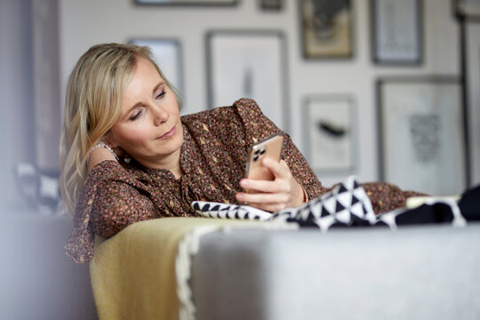Blond woman using cell phone at home