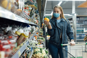 A woman in a medical mask buys groceries at a grocery store. Coronavirus, virus, infection, epidemic, pandemic. Russia