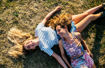 Happy young female friends relaxing on field during weekend