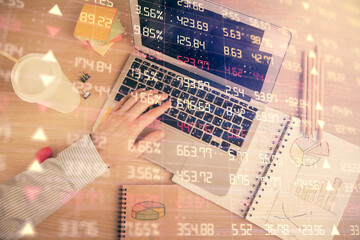 Double exposure of man's hands typing over computer keyboard and forex graph hologram drawing. Top view. Financial markets concept.