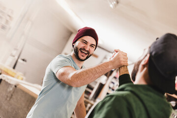 Two happy young men high fiving in workshop