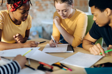 Young people sitting together at table and taking notes