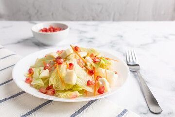 Lettuce and pomegranate salad on a white marble base. Healthy vegetarian food