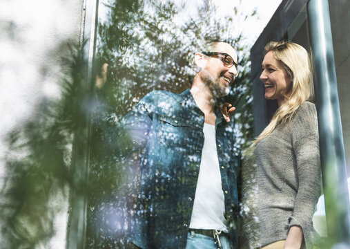 Laughing mature couple standing on terrace of their house