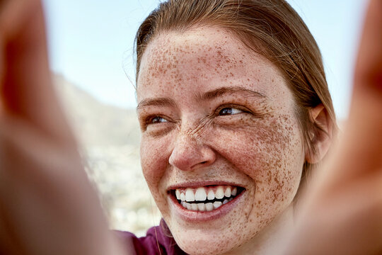 Portrait of laughing young woman with freckles outdoors
