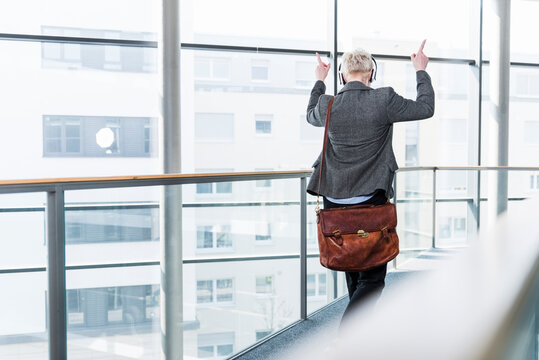 Woman on office floor enjoying listening to music with headphones