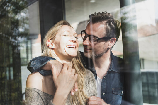 Happy mature couple behind windowpane at home