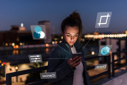 Young woman outdoors at night with data emerging from smartphone
