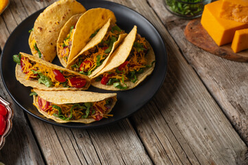 Plate with tasty mexican tacos on rustic wooden table with ingredients for cooking background. Concept of traditional meal. View from above. Recipe book with appetizing food. Space for text.
