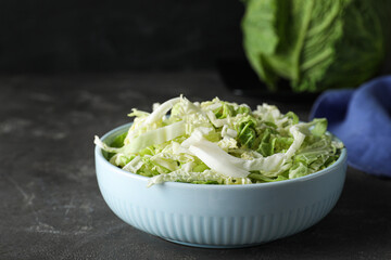 Cut fresh savoy cabbage in bowl on grey table, closeup