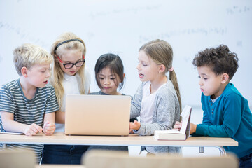 Pupils with laptop learning together in class