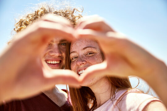 Happy young couple shaping a heart with their hands