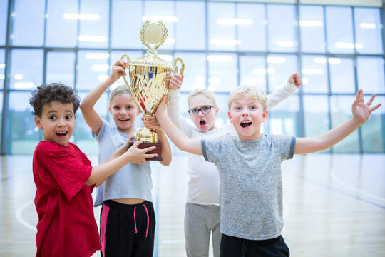 Happy pupils holding trophy in gym
