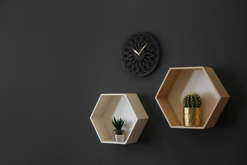 Clock and shelves with beautiful houseplants on black wall, space for text. Interior design