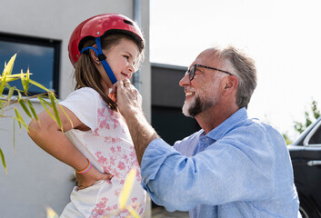Mature man fixing safety helmet on little girl's head