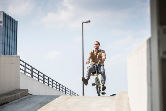 Laughing businessman riding down a ramp on his bicycle