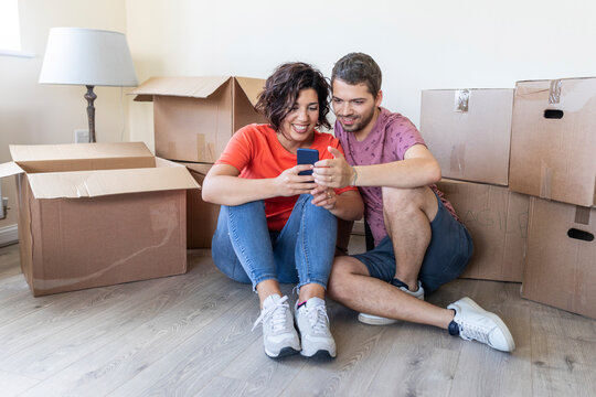 Happy couple using cell phone in new home