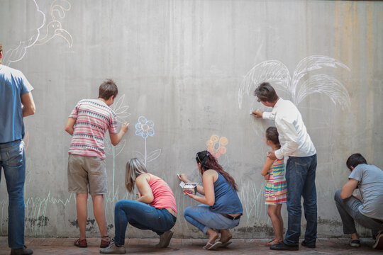 People drawing colourful pictures with chalk on a concrete wall