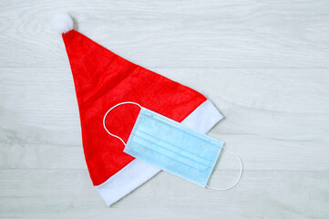 Red Christmas santa hat medical protective mask. Gray wooden background.