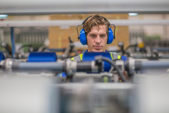 Man wearing ear defenders operating machine in factory