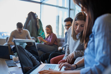 Group of friends sitting together in a cafe with laptop
